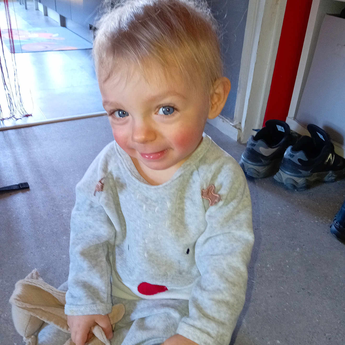 Dzihad a rejoint le concours — aidez-le/la à gagner de superbes lots ! toddler, child, smile, indoor, blue_eyes, rosy_cheeks, soft_toy, sitting, floor, casual_clothing, home, shoes, playful, cute, person, young_child, portrait, happy, candid, cozy