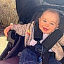 baby, bushes, casual, child, cute, denim_pants, face, happy, head, jacket, nature, outdoor, person, seatbelt, smiling, stone_wall, striped_socks, stroller, sunlight, winnie_the_pooh
