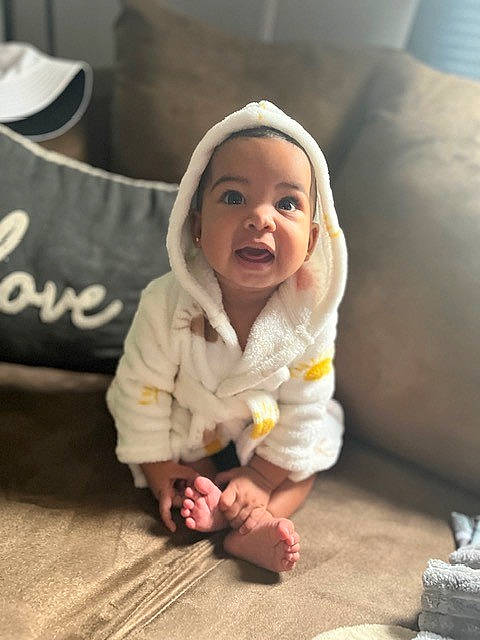 Aubrey is registered to the contest to win money with this photo: baby, baby_toddler_clothing, cheek, child, comfort, face, floor, flooring, foot, happy, head, headwear, linens, nose, outerwear, person, skin, sleeve, smile, textile