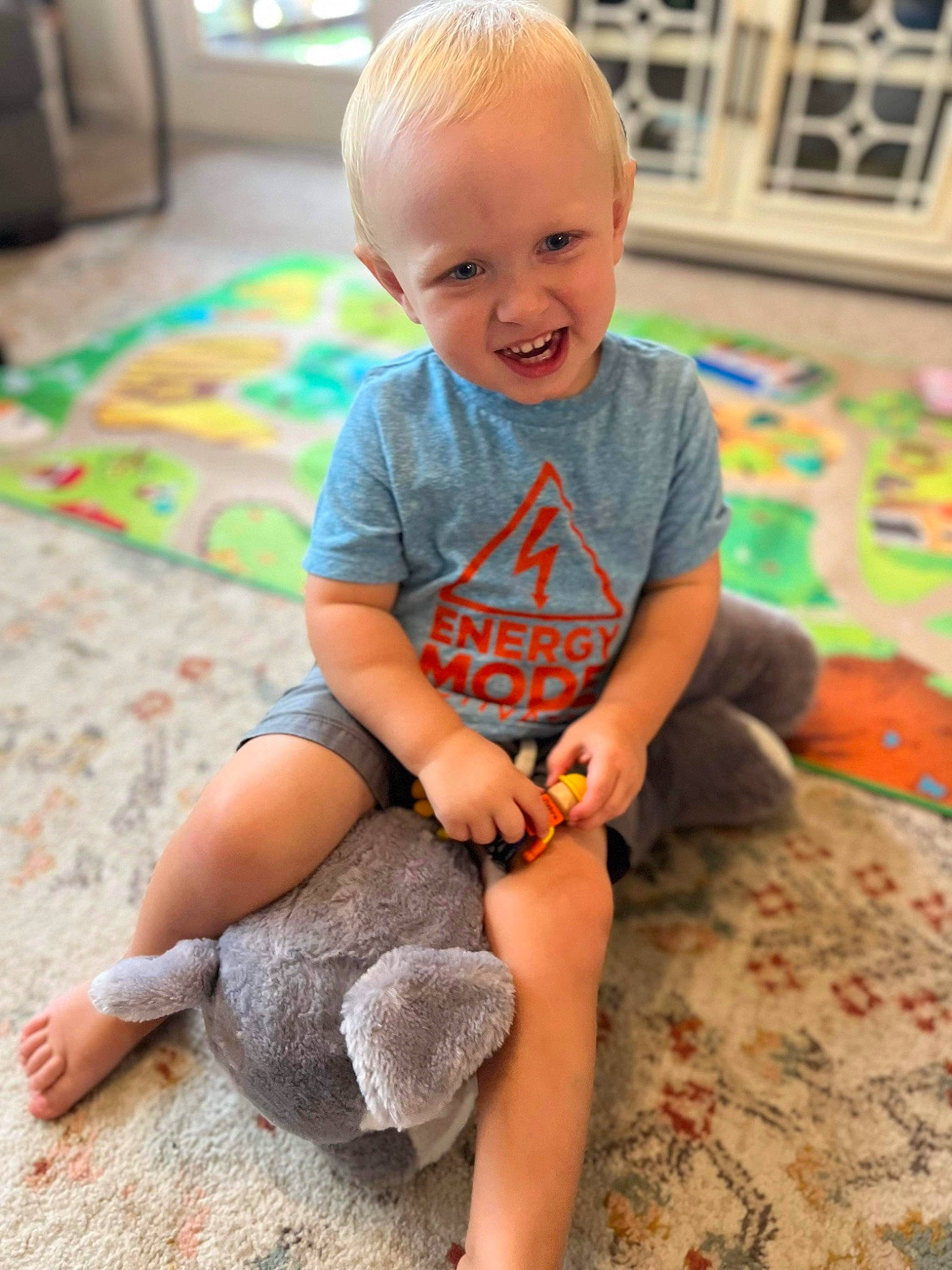 Oliver is registered to the contest to win money with this photo: baby, baby_toddler_clothing, child, face, floor, flooring, fun, happy, head, human_body, knee, person, shorts, skin, sleeve, smile, standing, t_shirt, thigh, toddler