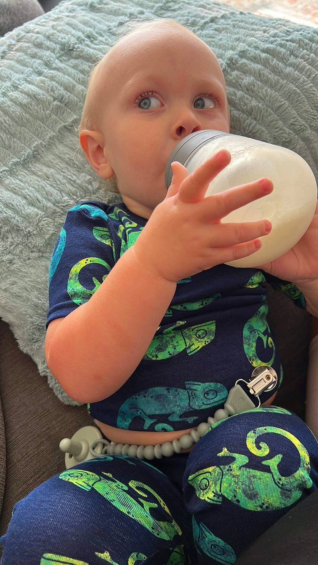 Oliver joined the competition — help win amazing prizes! baby_bottle, baby_toddler_clothing, cheek, drinkware, facial_expression, finger, gesture, green, hand, human_body, lip, mouth, nail, neck, nose, organ, person, product, skin, sleeve