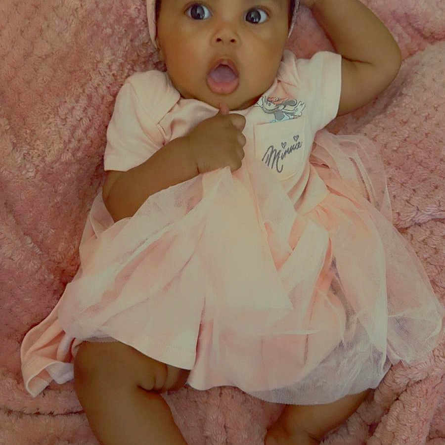 Sidiyah Lewis is registered to the contest to win money with this photo: baby, blanket, child, cozy, cute, fabric, foot, hand, headband, indoors, infant, lying_down, person, pink_dress, portrait, skin, soft_texture, surprised_expression, tulle, wide_eyes