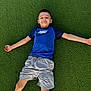 child, boy, smile, grass, outdoor, nike_shirt, shorts, casual_clothing, playing, fun, leisure, summer, relaxation, happy, young, person, nature, greenery, posing, recreation