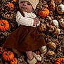 baby, infant, knit_hat, brown_dress, pumpkins, autumn, gourds, fall, cozy, cute, baby_booties, lying_down, seasonal, decor, warm_clothing, outdoor_style, harvest, small_face, child, adorable