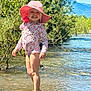 Lya a rejoint le concours — aidez-le/la à gagner de superbes lots ! child, smiling, pink_hat, floral_swimsuit, water, river, rocks, greenery, trees, sunlight, outdoor, nature, summer, mountains, sandals, happy, standing, shallow_water, blue_sky, playful