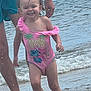 Lya participe au concours pour gagner de l'argent avec cette photo : toddler, child, beach, water, ocean, splashing, swimsuit, pink, cartoon, happy, smiling, adult, legs, summer, vacation, sand, waves, barefoot, outdoor, fun