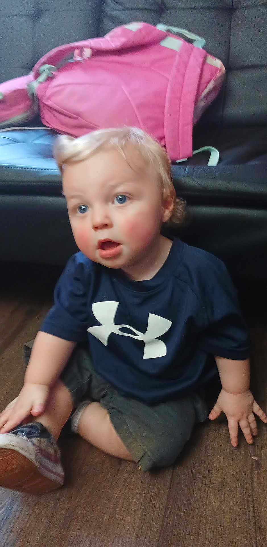 Kai joined the competition — help win amazing prizes! toddler, child, blue_eyes, rosy_cheeks, navy_shirt, sneakers, pink_backpack, wooden_floor, couch, indoor, sitting, curious, casual, shorts, person, young_child, small_hands, hair, face, clothing