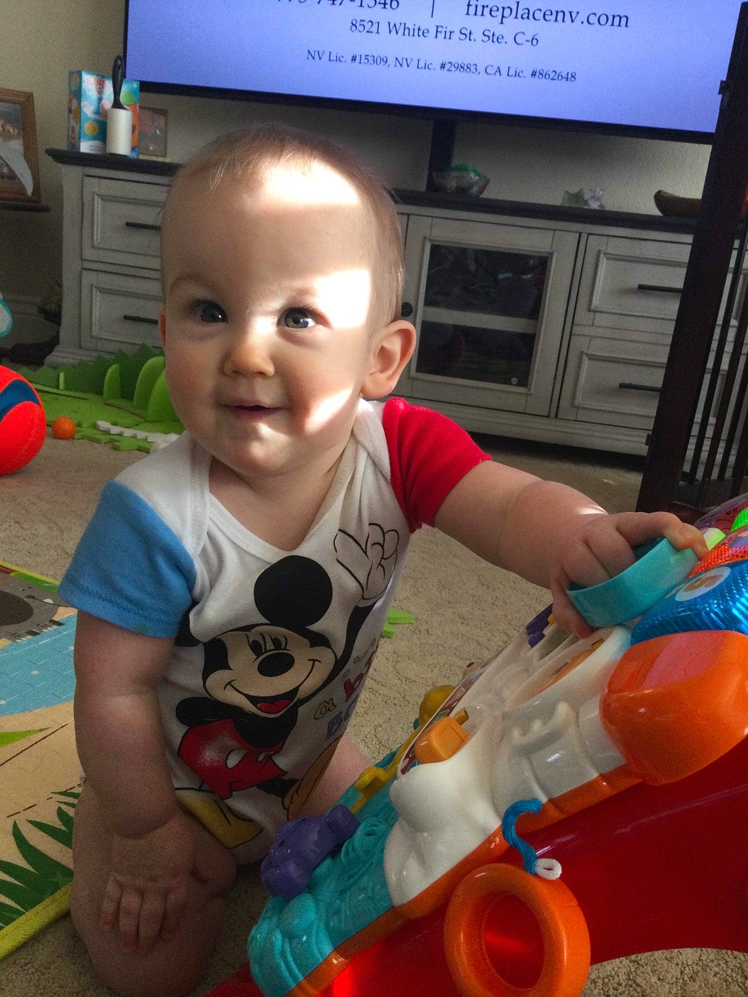 Travis joined the competition — help win amazing prizes! baby, blue, child, display_device, fictional_character, flooring, fun, home_appliance, lamp, organ, person, plastic, plastic_bottle, play, room, sitting, smile, t_shirt, television, toddler