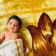 Nainika joined the competition — help win amazing prizes! baby, infant, child, blanket, floral_pattern, yellow, brown, cloth, wrapped, lying_down, cute, portrait, skin, face, expression, indoors, soft_texture, newborn, small_hand, curly_hair
