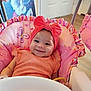 baby, baby_seat, butterfly_pattern, child, closeup, cute, decor, door, floor, happy, headband, indoor, infant, orange_clothing, pink, pink_bow, portrait, seat, smiling, toy