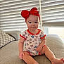 Paisley joined the competition — help win amazing prizes! baby, child, infant, red_bow, headband, onesie, patterned_clothing, sitting, couch, pillow, window_blinds, natural_light, indoors, smiling, cute, face, feet, hand, skin, furniture