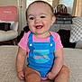 Paisley joined the competition — help win amazing prizes! baby, child, smiling, indoors, couch, clothing, pink_shirt, blue_overall_print, happy, face, legs, feet, living_room, window, chair, ceiling_fan, home, furniture, portrait, infant