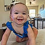baby, child, smiling, crawling, blue_dress, indoor, living_room, table, chair, ceiling_fan, window, floor, person, cute, happy, tooth, hair_bow, skin, furniture, home