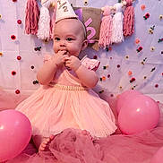 Ivy is registered to the contest to win money with this photo: baby, infant, birthday, party_hat, pink_dress, balloons, tulle, celebration, tassels, decorations, cute, smiling, sitting, indoors, face, child, festive, young_child, adorable, background