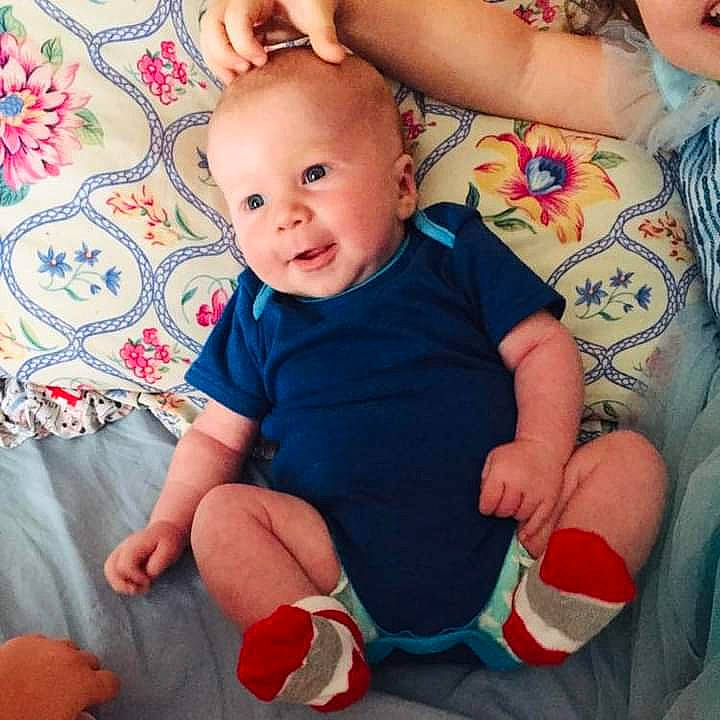 Sean is registered to the contest to win money with this photo: arm, baby, baby_toddler_clothing, cheek, child, comfort, facial_expression, finger, hand, happy, pattern, people, person, pink, product, red, skin, sleeve, smile, textile