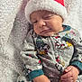 baby, infant, santa_hat, winking, onesie, mickey_mouse, holiday, christmas, blanket, cute, smiling, festive, soft_texture, sleepwear, child, portrait, hand, cozy, relaxed, indoors