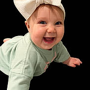 Sadi is registered to the contest to win money with this photo: baby, child, smile, bow, headband, crawling, green_clothing, cute, happy, face, infant, portrait, young_child, expression, hands, eyes, background_black, clothing, person, indoors