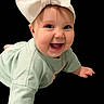 baby, child, smile, bow, headband, crawling, green_clothing, cute, happy, face, infant, portrait, young_child, expression, hands, eyes, background_black, clothing, person, indoors