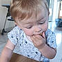 casual, child, crumbs, curious, eating, face, floor_tiles, hand, home, indoor, kitchen, light_brown_hair, muffin, natural_light, person, short_sleeve_shirt, space_pattern, table, toddler, wooden_table