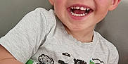 Swann a rejoint le concours — aidez-le/la à gagner de superbes lots ! casual_clothing, child, couch, cute, face, gray_shirt, hand, happy, indoor, orange_toy, person, playful, short_hair, sitting, skin, smiling, teeth, toddler, toy, young