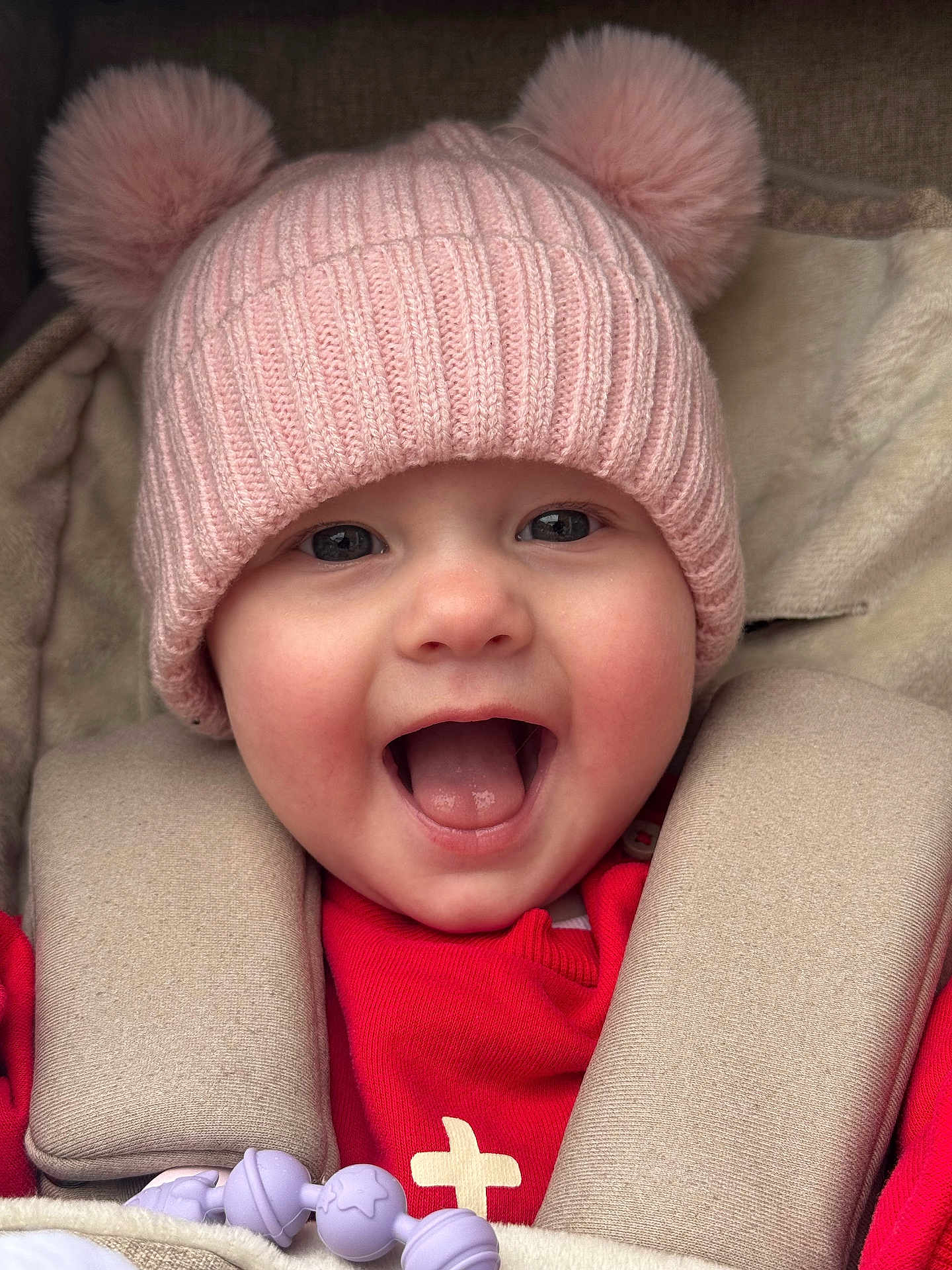 Verity joined the competition — help win amazing prizes! baby, child, smiling, pink_hat, pom_poms, knitwear, red_clothing, car_seat, happy, cute, face, portrait, infant, warm_clothing, closeup, adorable, cheerful, young_child, headwear, seatbelt