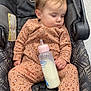 baby, sleeping, car_seat, milk_bottle, onesie, infant, child, toddler, clothing, pattern, leopard_print, hand, face, hair, floor, seatbelt, comfort, indoors, peaceful, rest