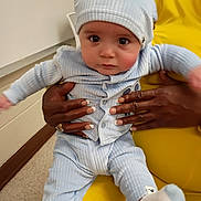 Sebastian joined the competition — help win amazing prizes! baby, child, person, clothing, hat, socks, hand, nail_polish, chair, yellow_chair, indoor, floor, wall, buttons, seated, looking_at_camera, cute, infant, skin, fingers