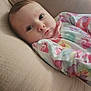 baby, infant, face, cushion, fabric, clothing, onesie, floral_pattern, skin, head, eyes, cheeks, indoor, soft_texture, comfort, portrait, child, cute, resting, young