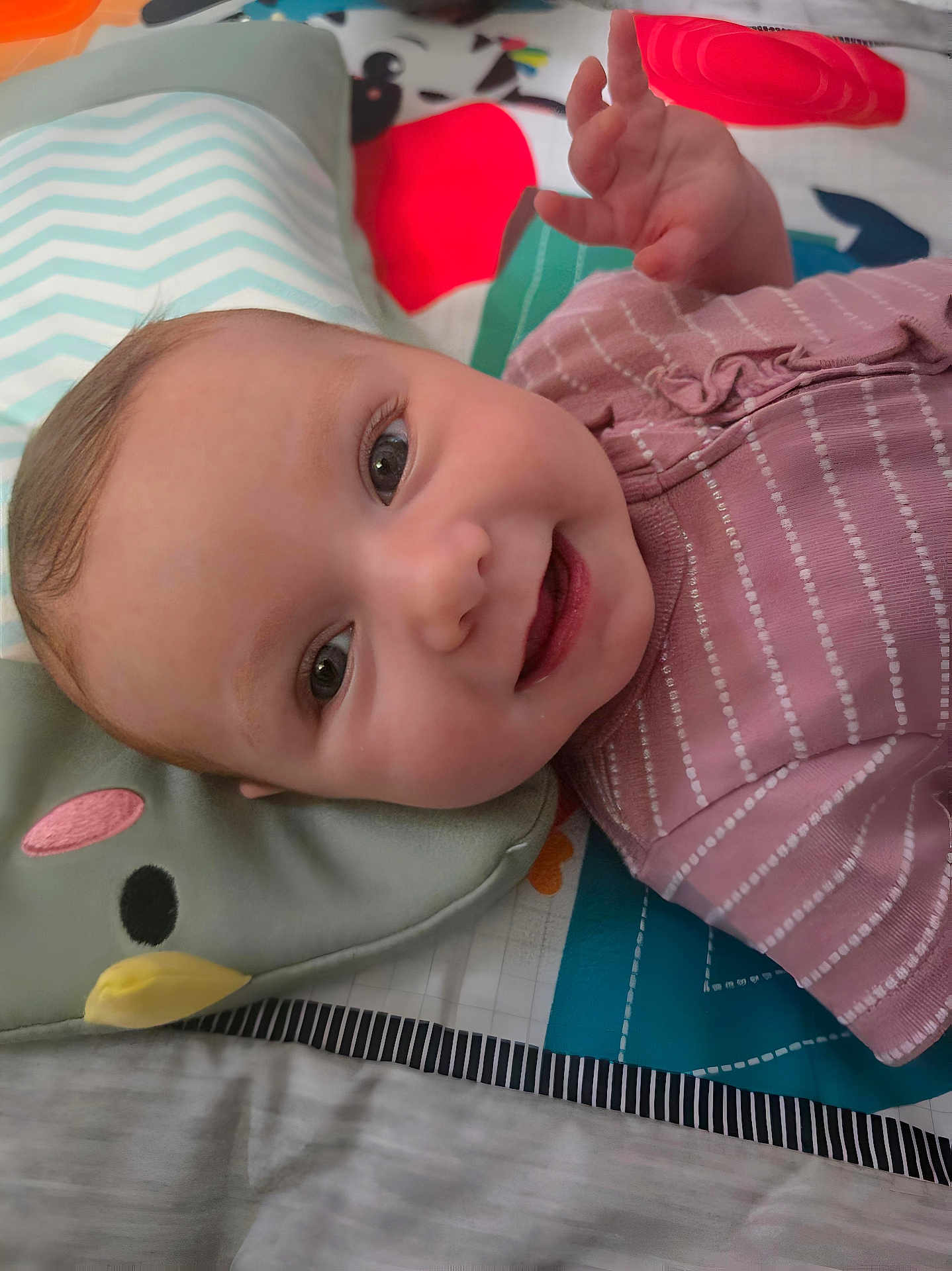 Peyton joined the competition — help win amazing prizes! baby, smiling, infant, face, pink_clothing, striped, lying_down, playmat, pillow, animal_pillow, cute, happy, child, indoors, closeup, young_child, hand, skin, head, eyes