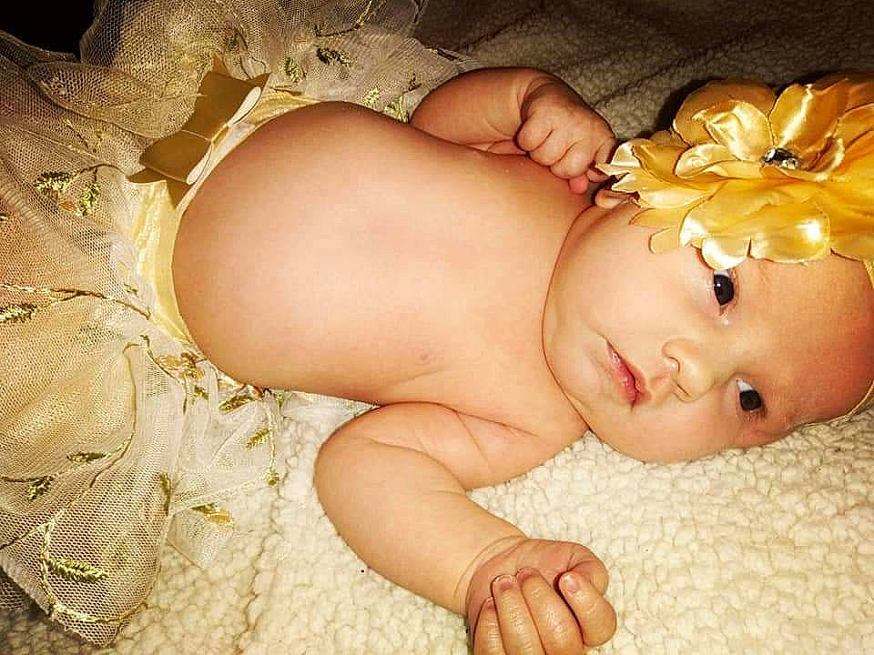 Amelia Christine Collins is registered to the contest to win money with this photo: arm, baby, baby_toddler_clothing, cheek, chest, comfort, eye, fashion_accessory, grass, hand, headband, headpiece, human_body, mouth, nail, person, skin, stomach, thumb, toddler