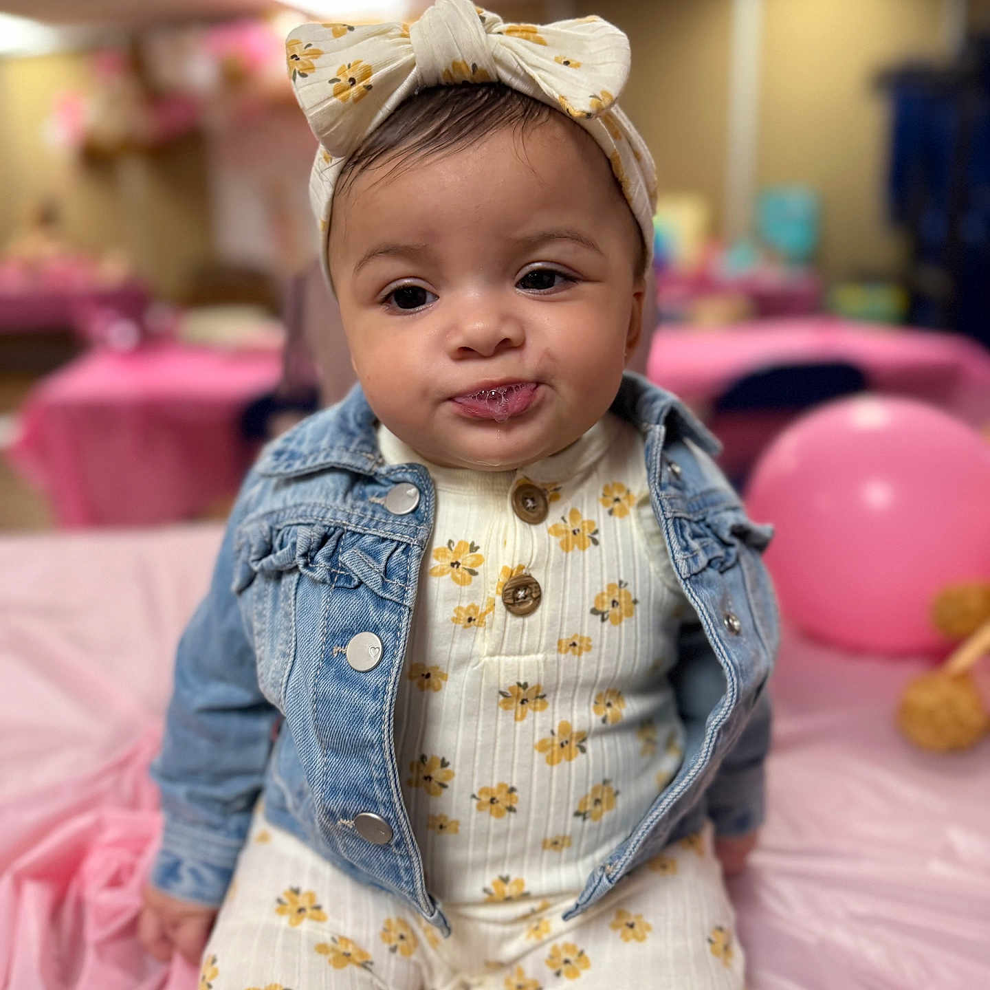 Jyra joined the competition — help win amazing prizes! baby, blurred_background, celebration, child, clothing, cute, denim_jacket, drool, expression, face, flower_pattern, headband, indoor, infant, onesie, party, pink_balloon, portrait, sitting, tablecloth
