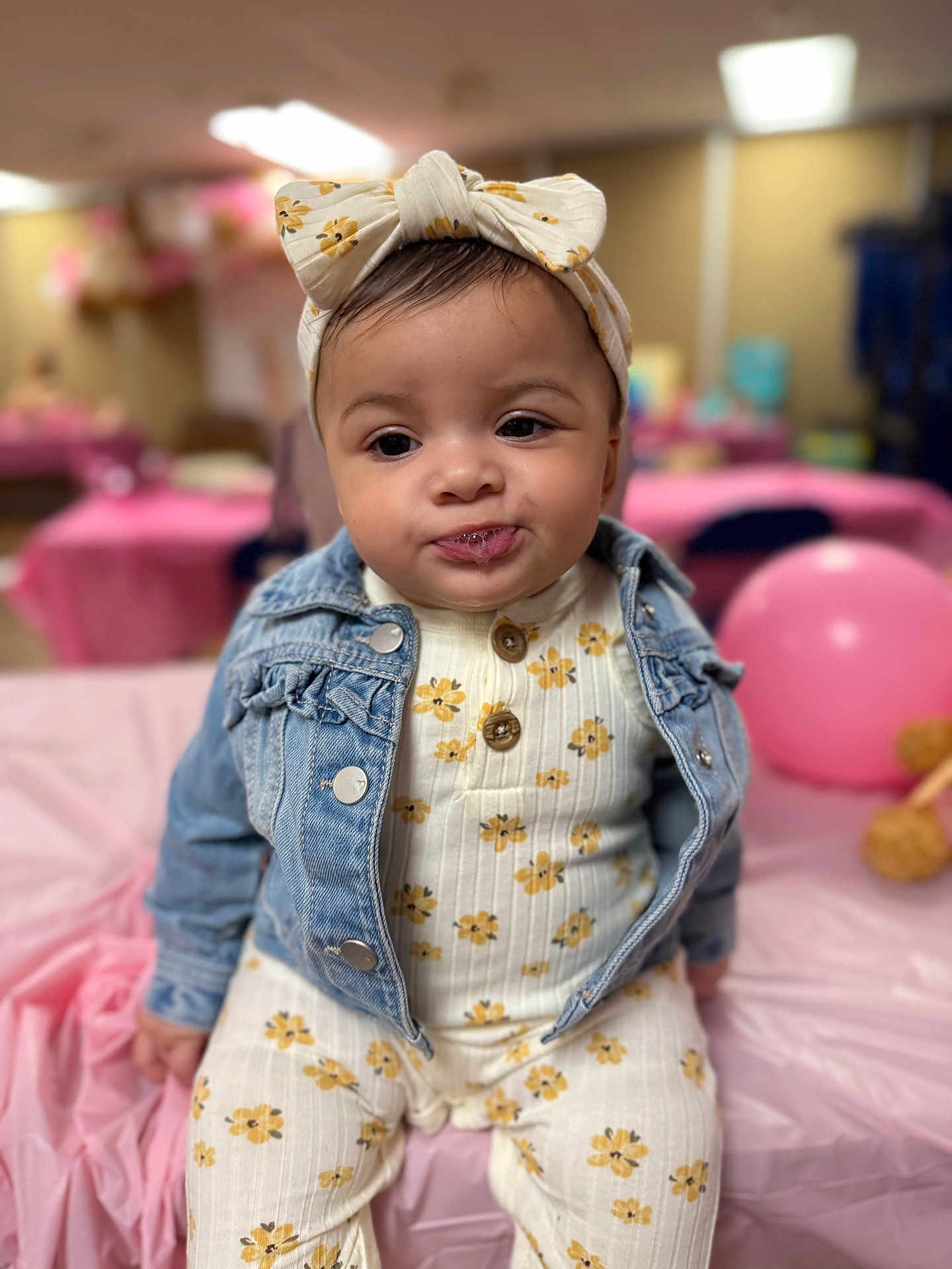 Jyra joined the competition — help win amazing prizes! baby, child, infant, denim_jacket, headband, flower_pattern, onesie, drool, pink_balloon, party, tablecloth, indoor, cute, portrait, sitting, expression, blurred_background, celebration, clothing, face