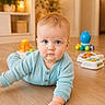 baby, blue_eyes, child, crawling, floor, hand, indoor, light_wood_floor, looking_at_camera, orange_toy, person, playing, reaching, sleepsuit, soft_lighting, toy, wood_floor, young_child, blue_clothing, home