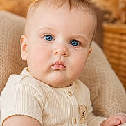 Aaron is registered to the contest to win money with this photo: baby, blue_eyes, knit_clothing, teddy_bear, portrait, child, infant, close_up, seated, beige, chair, soft_lighting, warm_tones, indoor, cute, texture, face, expression, person, young_child