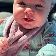 Haven joined the competition — help win amazing prizes! baby, infant, child, face, close_up, smiling, bib, onesie, cherry_pattern, hand, eyes, cheeks, forehead, eyelashes, sunlight, portrait, adorable, cozy, car_interior, shallow_depth_of_field