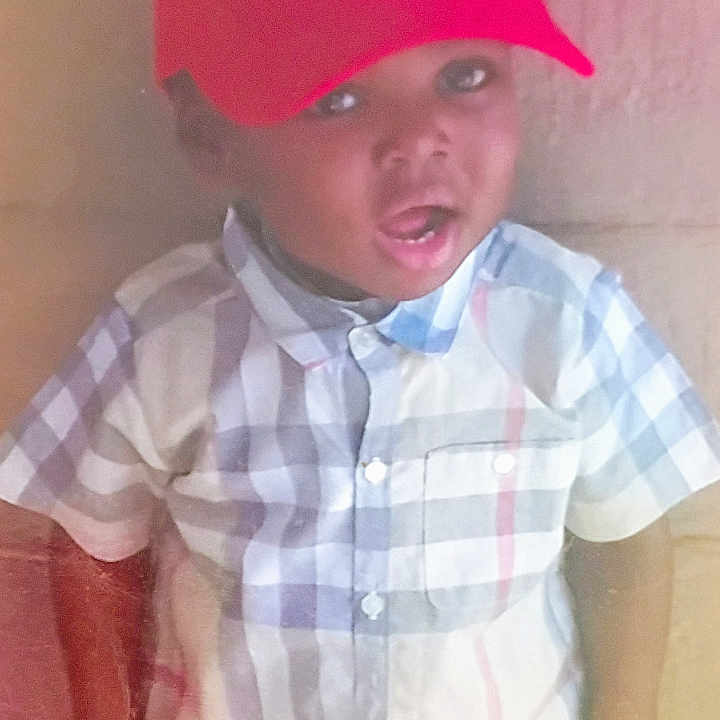 Jordan is registered to the contest to win money with this photo: background, buttoned_shirt, casual_clothing, checkered_shirt, child, cute, expression, eyes, face, headwear, indoor, light, mouth_open, person, portrait, red_cap, short_sleeve, sitting, skin_tone, young_child