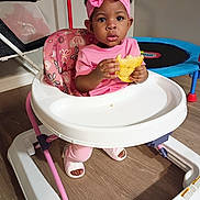 Saniyah Heaven joined the competition — help win amazing prizes! toddler, baby, pink_clothing, headband, baby_walker, food, indoor, flooring, toy, trampoline, cute, child, young_child, person, expression, sitting, footwear, play, curious, home