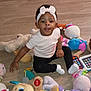 toddler, child, headband, white, bow, toy, stuffed_animal, floor, playtime, black_pants, white_shirt, socks, colorful, smile, indoor, cute, baby, person, sitting, fun