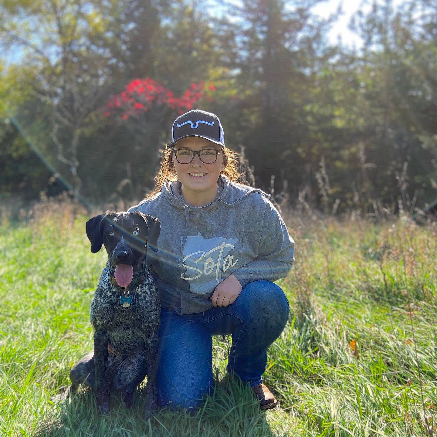 Bella is registered to the contest to win money with this photo: baseball_cap, cap, carnivore, companion_dog, dog, dog_breed, fawn, grass, grassland, happy, jeans, landscape, mammal, meadow, plant, prairie, smile, sunglasses, tree, vertebrate