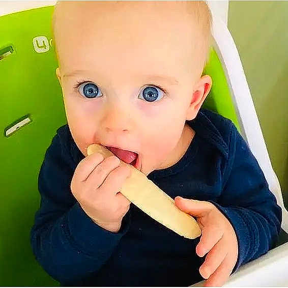 Adfwef joined the competition — help win amazing prizes! baby, child, infant, face, eyes, blue_eyes, smiling, eating, snack, food, hands, high_chair, indoor, portrait, sitting, navy_clothing, green_background, close_up, adorable, photography
