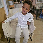 Soann participe au concours pour gagner de l'argent avec cette photo : background, boy, casual, chair, child, cozy, floor, furniture, happy, home, indoor, kitchen, light, person, portrait, relaxed, smile, table, white_clothing, young
