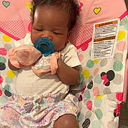 Jaylani joined the competition — help win amazing prizes! baby, infant, pacifier, mittens, pink, striped_socks, baby_seat, minnie_mouse, curly_hair, colorful, polka_dots, cute, child, indoors, comfortable, clothing, patterned, sitting, young, person
