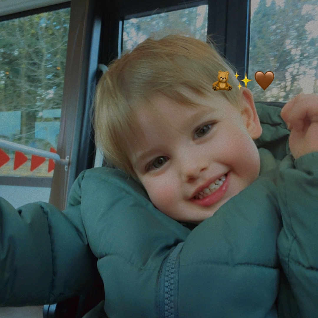 Ekloan participe au concours pour gagner de l'argent avec cette photo : child, smile, puffy_jacket, bus, window, seatbelt, indoors, happy, blonde_hair, face, cute, emojis, teddy_bear, sparkle, winter_clothing, young_child, seat, casual, daylight, portrait