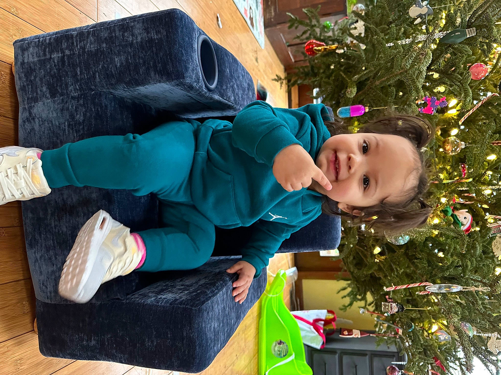 Amora is registered to the contest to win money with this photo: bag, child, christmas_decoration, christmas_ornament, christmas_tree, event, fir, fun, grass, happy, holiday, holiday_ornament, joy, leisure, ornament, person, plant, sitting, sock, toddler
