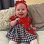 Tahleah is registered to the contest to win money with this photo: baby, cheerful, child, clothing, couch, cute, dress, happy, headwear, indoor, infant, person, pillow, portrait, red_headband, sitting, smiling, strawberry_pattern, toddler, white_tights