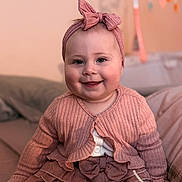 Tahleah is registered to the contest to win money with this photo: baby, baby_shoes, bow, child, couch, cute, face, happy, headband, home, indoors, infant, layered_skirt, pink_clothing, portrait, ribbon, sitting, smiling, soft_toys, warm_lighting