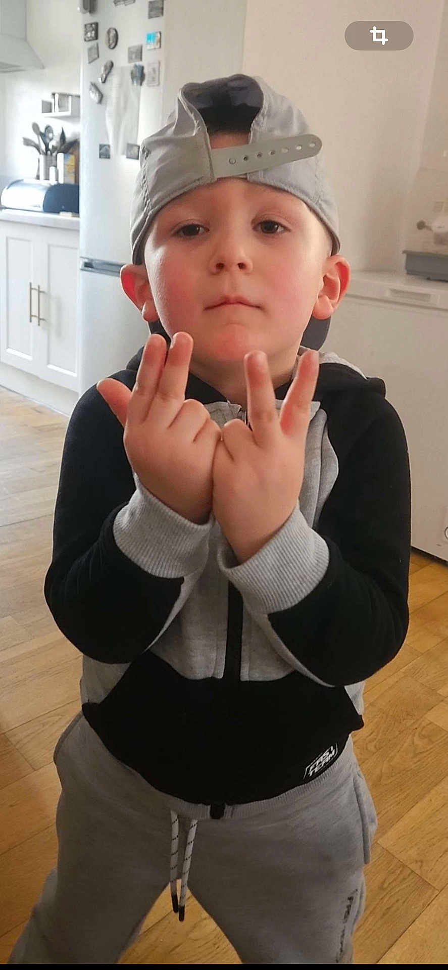 Lymëo a rejoint le concours — aidez-le/la à gagner de superbes lots ! child, boy, cap, baseball_cap, hoodie, sweatpants, hand_gesture, pose, face, ears, kitchen, refrigerator, wooden_floor, indoors, portrait, standing, expressionless, casual_clothing, young_child, home