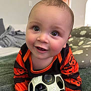 Carter joined the competition — help win amazing prizes! baby, smiling, toy, ball, orange_clothing, black_clothing, pumpkin_pattern, indoor, blanket, happy, face, child, crawling, closeup, cute, infant, soft_light, home, portrait, playful