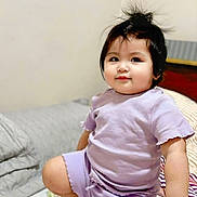 Sofia joined the competition — help win amazing prizes! toddler, child, baby, face, smile, hair, purple_clothing, bed, bedspread, floral_pattern, pillow, indoor, skin, hand, foot, cute, person, young_child, clothing, kneeling