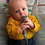 baby, infant, pacifier, yellow_shirt, denim_pants, hands, face, blue_eyes, indoor, sitting, cute, child, clothing, background, warning_label, colorful, closeup, expression, young, comfort